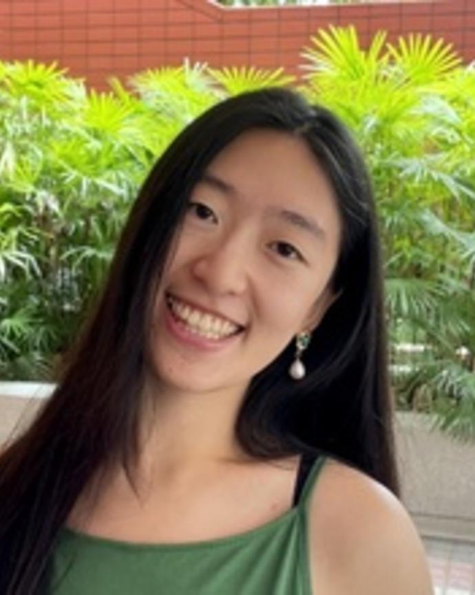 A Chinese woman in a green dress smiles for the camera.